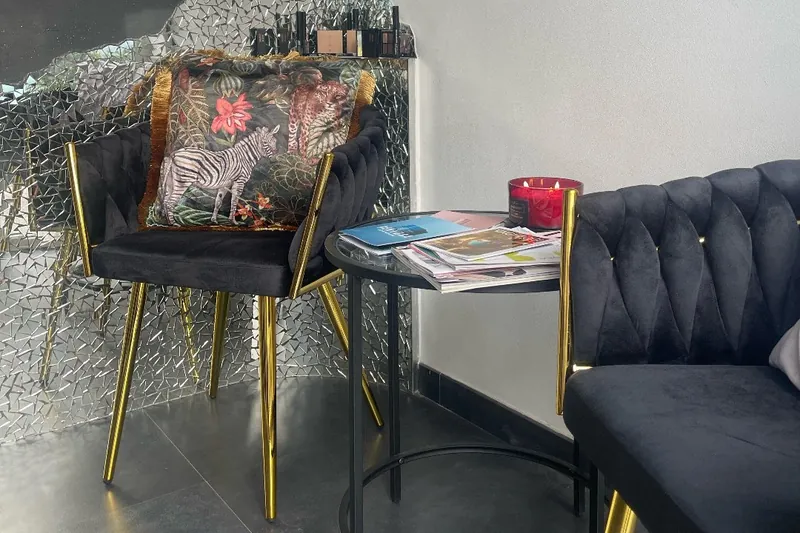 L'angolo d'attesa con poltroncine in velluto nero e gambe dorate davanti alla parete a specchi
