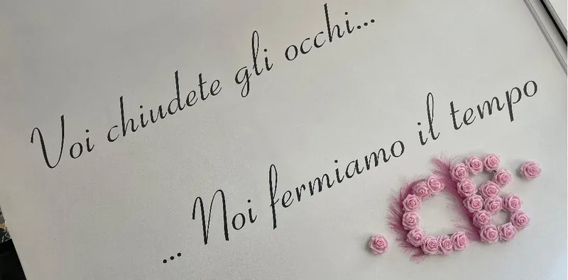 La parete del centro con la scritta Voi chiudete gli occhi, noi fermiamo il tempo e il monogramma in rose rosa